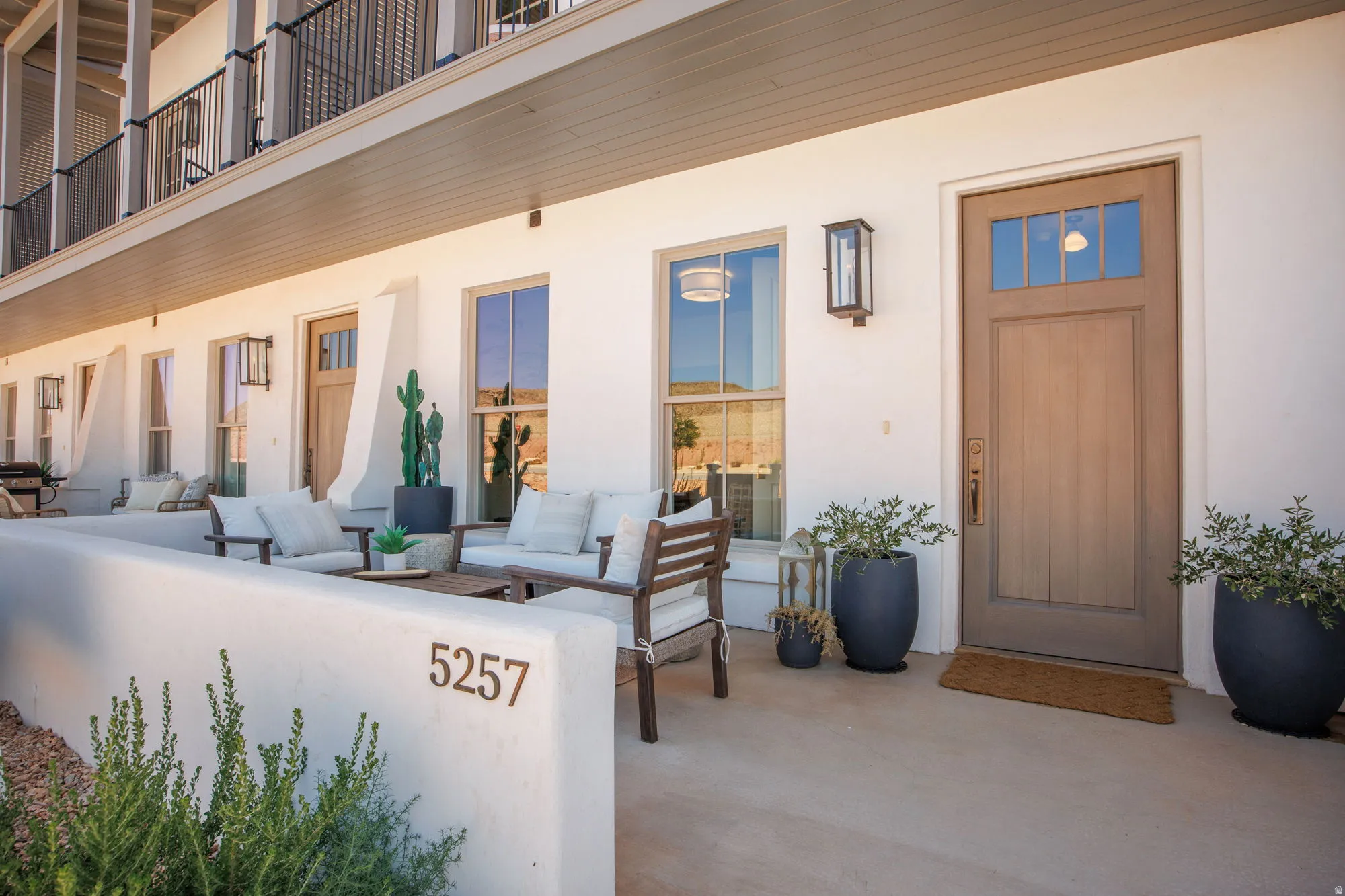 Entryway featuring a wood-panel door with transom windows, a wall-mounted exterior light fixture, and a concrete patio