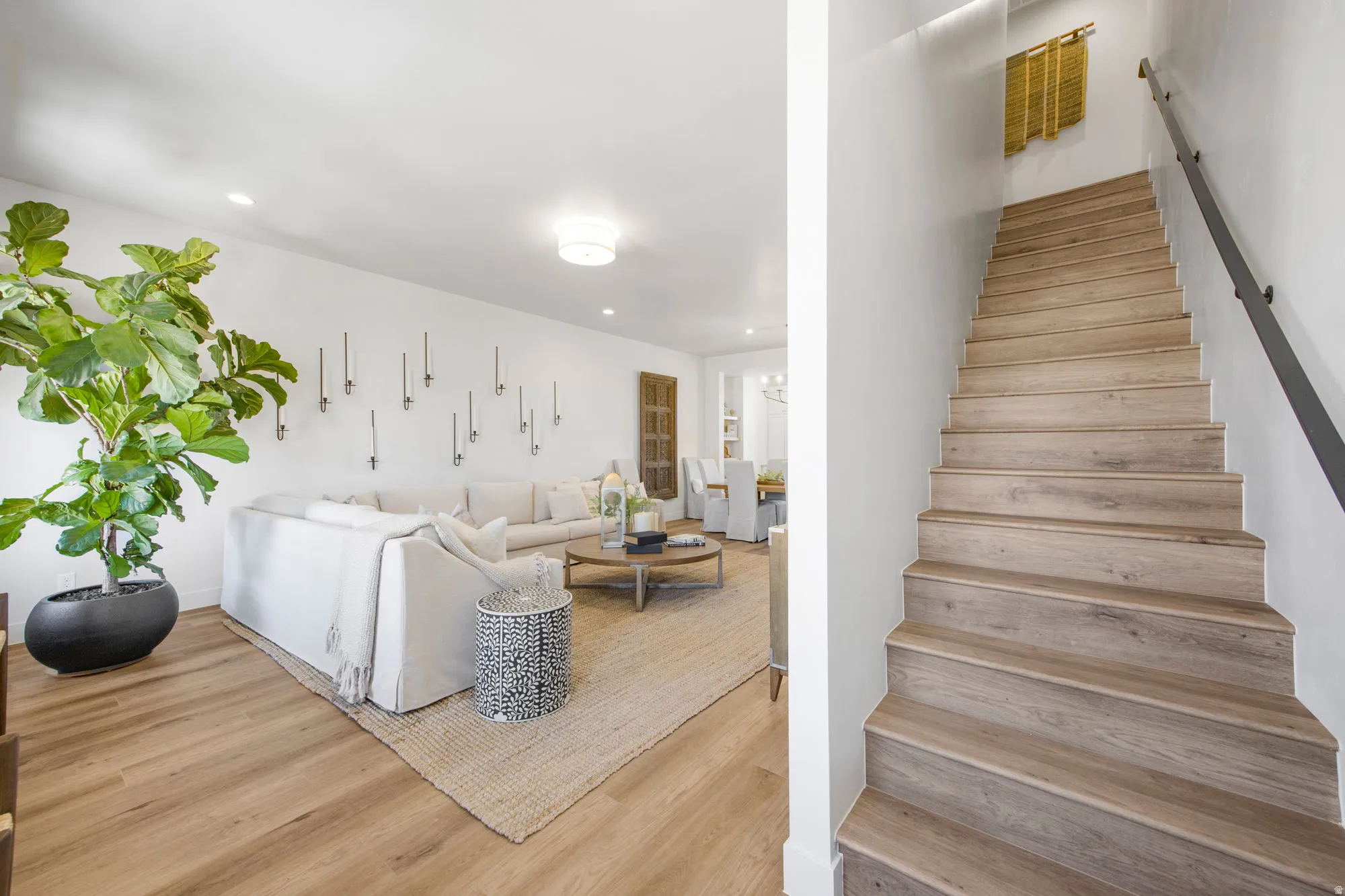 Hardwood staircase with a black handrail and recessed lighting