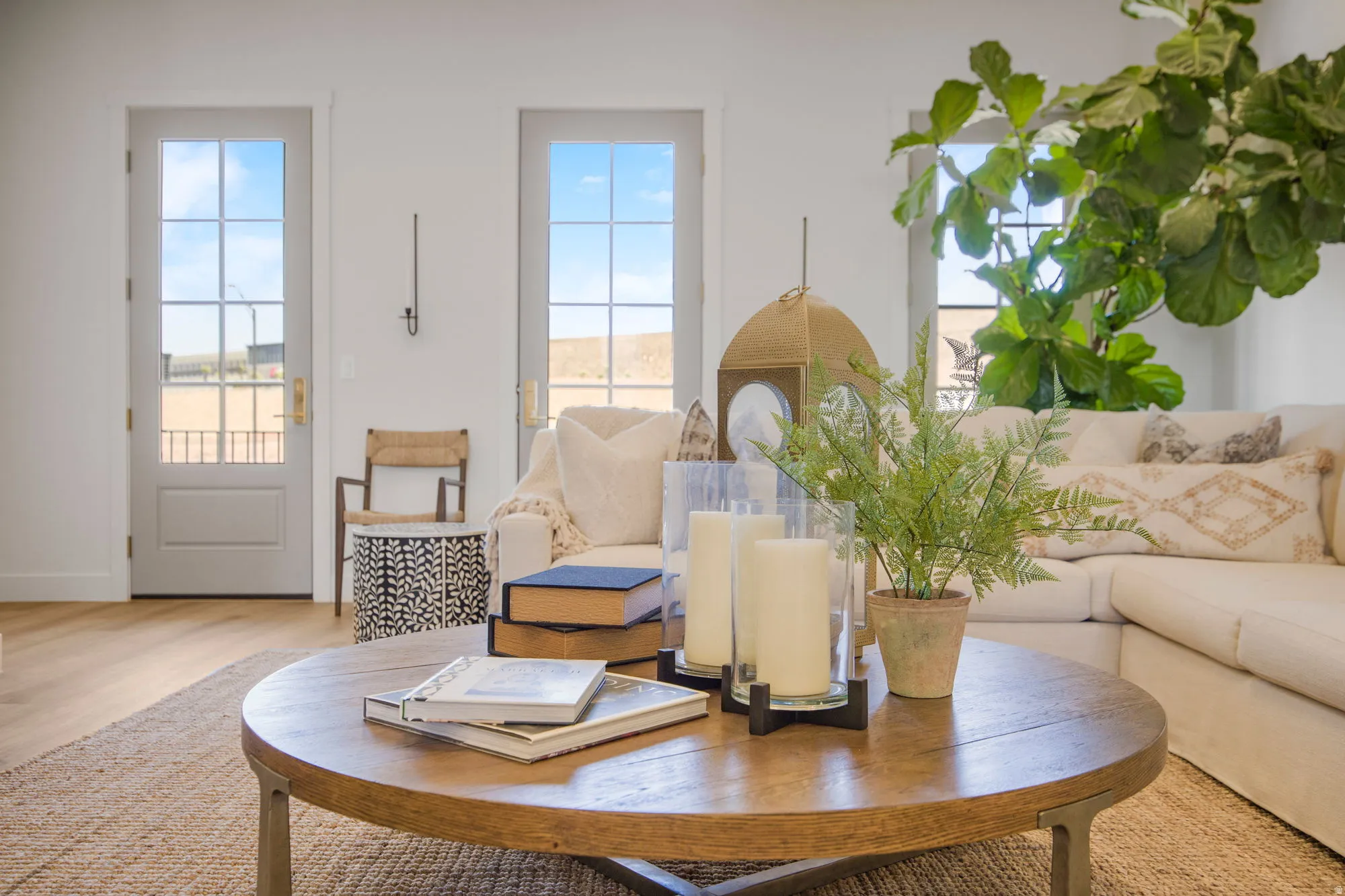 Bright interior space featuring light wood-finish flooring, white walls, and multiple light-colored French doors with grid-patterned glass