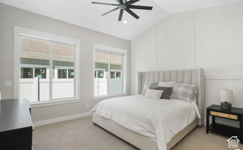 Vaulted ceiling with a contemporary ceiling fan, two large windows, light gray walls, and plush carpeting