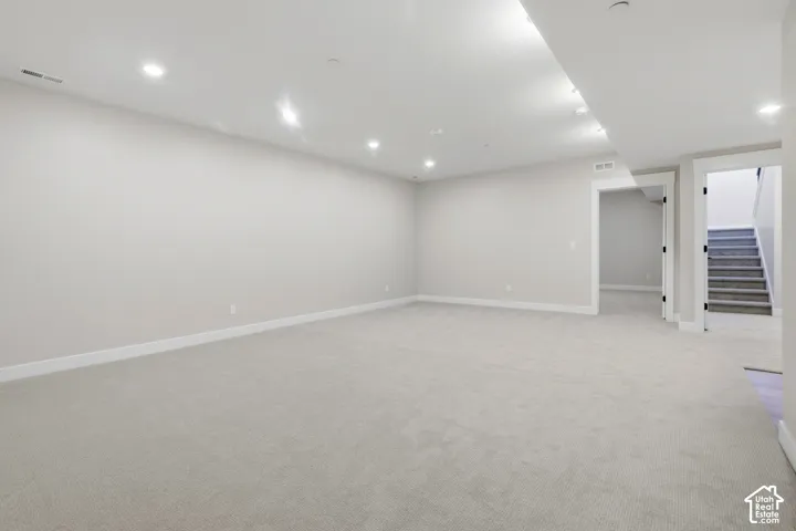 Expansive open space with light gray wall paint, recessed lighting, plush carpeting, and white trim