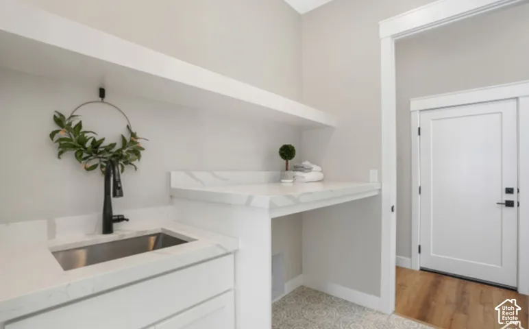 Laundry area featuring a stainless steel sink, black-finish faucet, quartz-finish countertops, and built-in shelving
