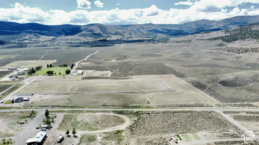 Expansive acreage with established road infrastructure, visible mountain range, and scattered mature trees