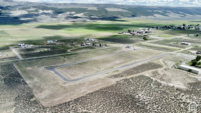 Expansive undeveloped land with a paved road, scattered structures, and distant mountains