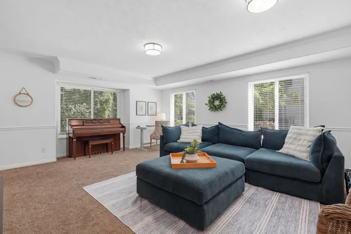 Carpeted living area featuring multiple windows, a coffered ceiling, and crown molding