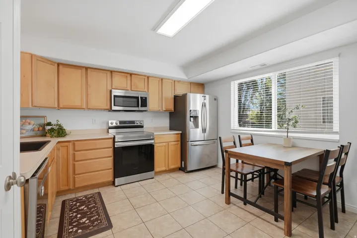 Kitchen featuring stainless steel appliances, wood-finish cabinetry, tile flooring, and a large window