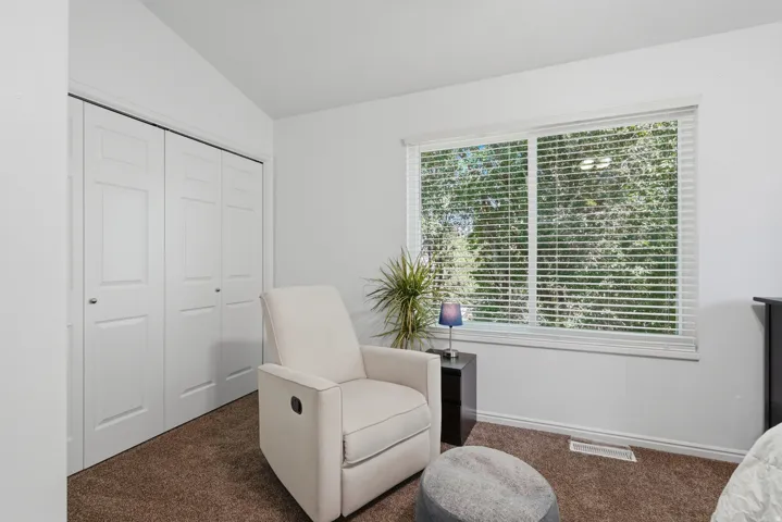 White walls with textured brown carpeting, featuring a window with white blinds