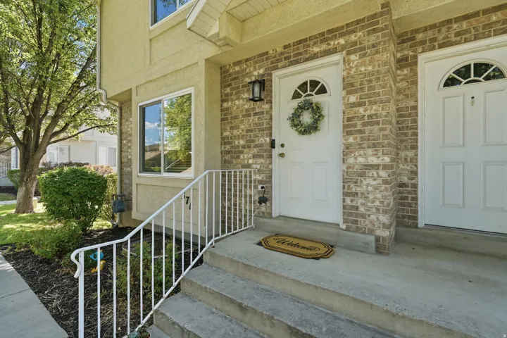 Brick facade with a white paneled entry door featuring an arched transom and an exterior wall lantern