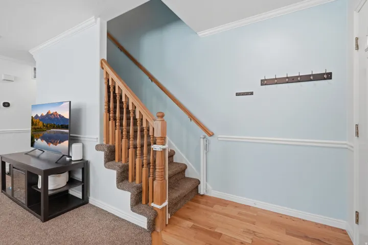 Staircase featuring wood balusters and handrail, carpeted treads, and wood-finish flooring at the base