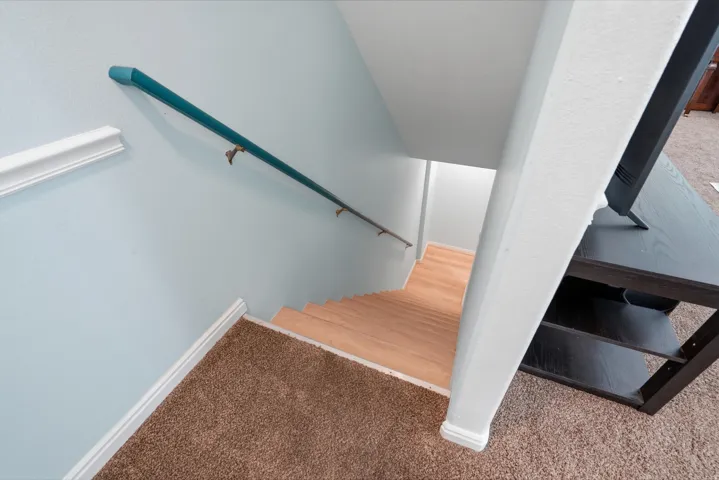 Stairway featuring wood-finish treads and a teal handrail