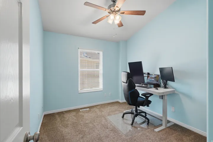 Ceiling fan with light fixture, single window with blinds, light blue wall paint, and brown carpet flooring