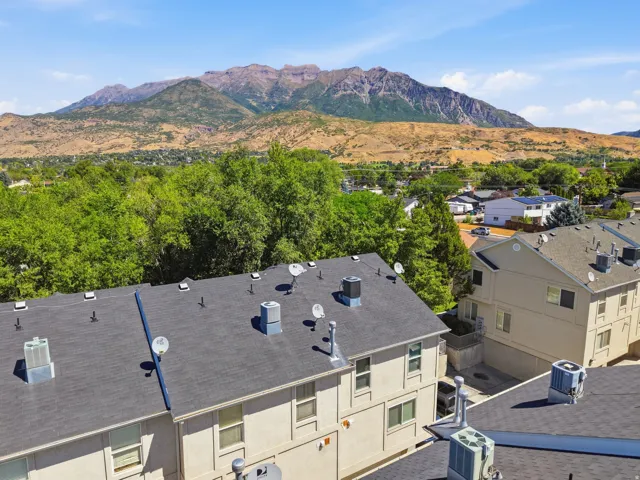 Mountain scenery, natural landscape, multiple residential structures, mature trees, clear sky
