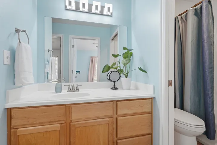 Wood-finish vanity with an integrated sink, polished chrome faucet, and expansive mirror
