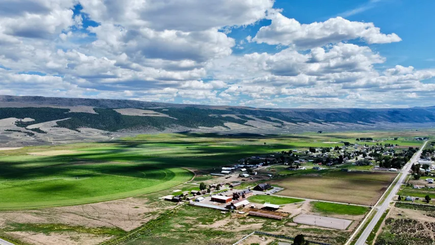 Expansive rural landscape featuring a highway, distant structures, and agricultural fields