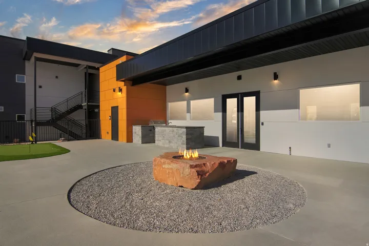 Contemporary exterior with an outdoor kitchen, rock fire pit, and putting green