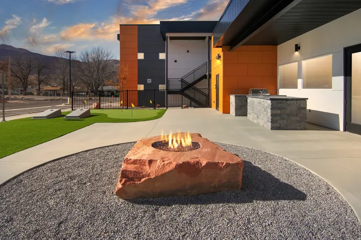 Outdoor living area featuring a stone fire pit, built-in BBQ station, artificial turf putting green, and concrete pathways