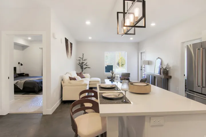 Open-concept living space with recessed lighting, a modern linear chandelier, and a kitchen island featuring a light-colored countertop