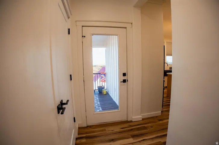 Wood-finish flooring, white walls, and a glass-paneled door with black hardware