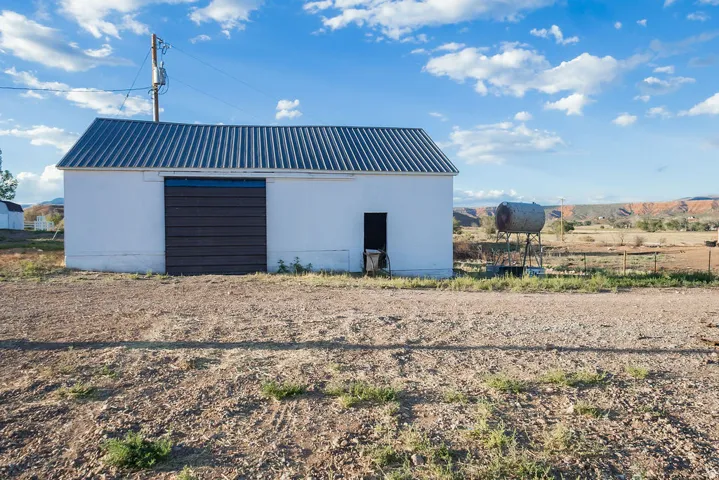 White-painted outbuilding with a corrugated metal roof and a large sliding door