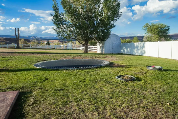 Expansive grass lawn with a white privacy fence and a white split-rail fence