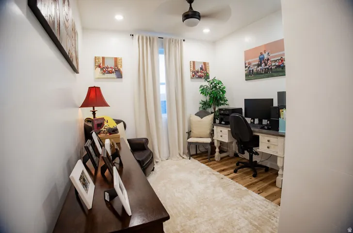 Recessed lighting, ceiling fan, wood-finish flooring, neutral wall tones, and full-height window with drapery