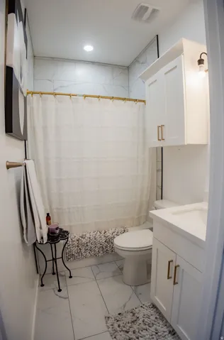 White shaker vanity with gold-finish hardware, single basin sink, and integrated countertop