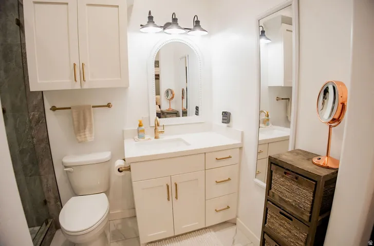 White vanity with a single basin sink, gold-finish faucet, and coordinating hardware