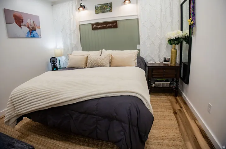 Hardwood flooring, painted accent wall, wall-mounted lighting fixtures, white trim, and a white wall finish