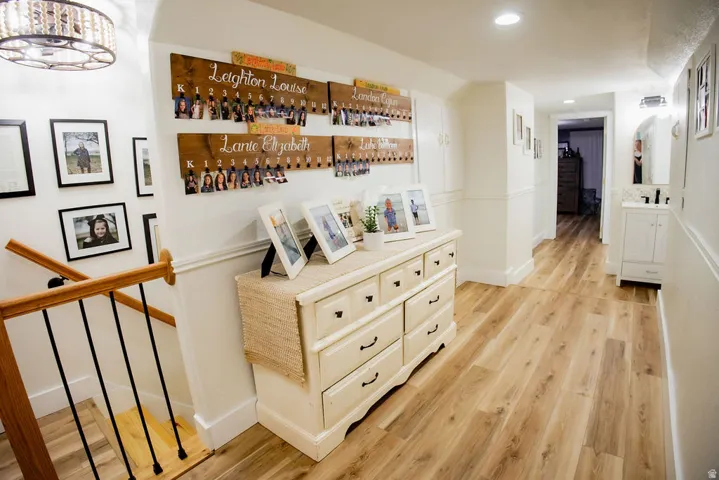 Wood-finish flooring throughout the hallway and staircase, featuring white wainscoting and wall paneling