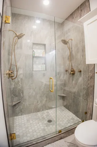 Enclosed shower with full-height tile walls, dual shower heads, and an integrated recessed niche