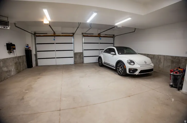 Two overhead garage doors, concrete flooring, and fluorescent ceiling lighting