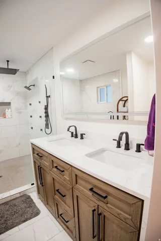 Dual vanity with wood-finish cabinetry, integrated sinks, and matte black fixtures