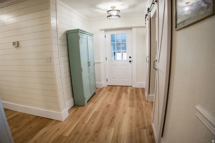 Hardwood-finish flooring, shiplap accent wall, white panel doors, barn-style sliding doors, and a flush-mount ceiling light fixture