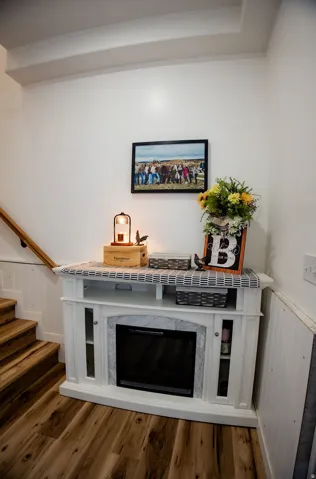 White built-in media console with a faux fireplace insert, marble-look surround, and glass-front cabinets