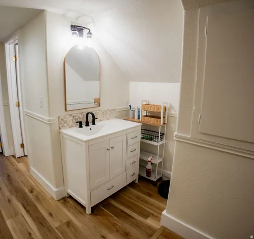 White vanity with cabinet storage and drawers, featuring a white basin and matte black faucet