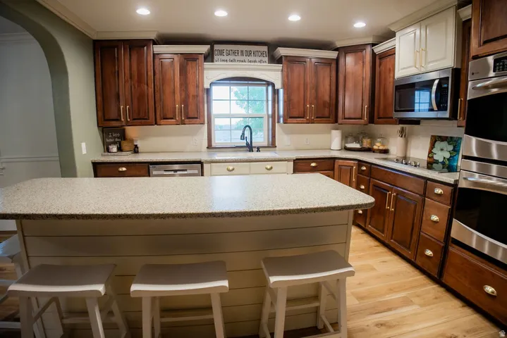 Spacious kitchen featuring an expansive island, rich wood cabinetry, stainless steel appliances, a built-in microwave, and recessed lighting