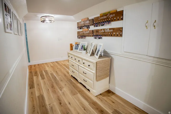 White walls with wood-finish flooring, recessed built-in cabinetry, and a decorative ceiling light fixture