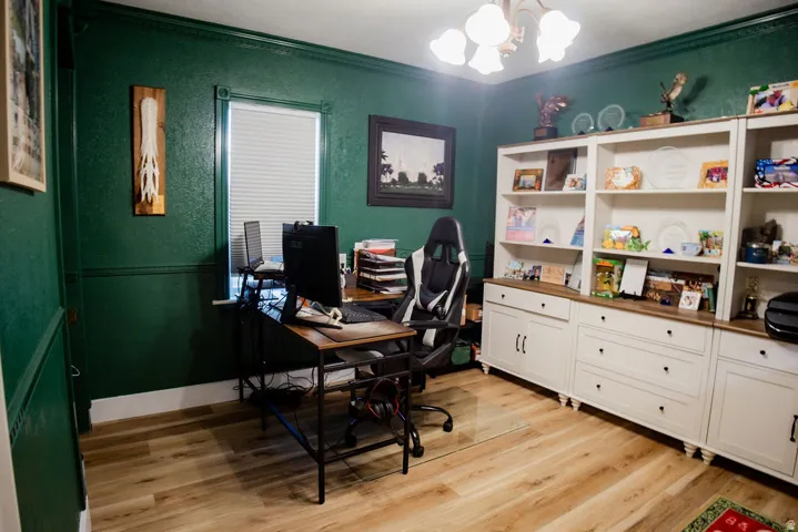 Wood-finish flooring, built-in shelving, built-in cabinetry, crown molding, and a chandelier