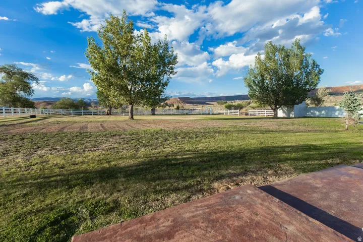 Expansive exterior grounds featuring mature trees, a white picket fence, and a distant mountain backdrop