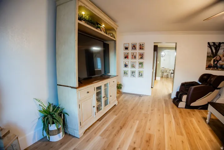Light wood-finish flooring throughout, featuring a built-in entertainment center with upper display lighting