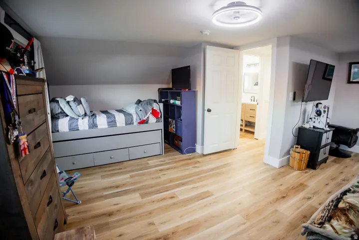 Wood-finish flooring, white trim, recessed lighting, and a sloped ceiling