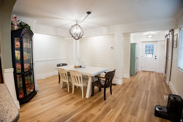 Wood-finish flooring throughout, white shiplap accent wall, crown molding, and a decorative chandelier