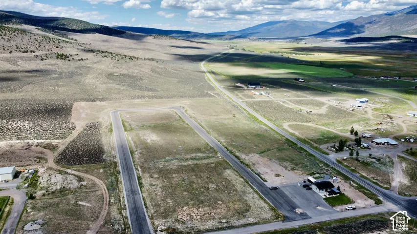 Expansive land featuring paved roadways, surrounding natural terrain, distant mountains, and scattered structures