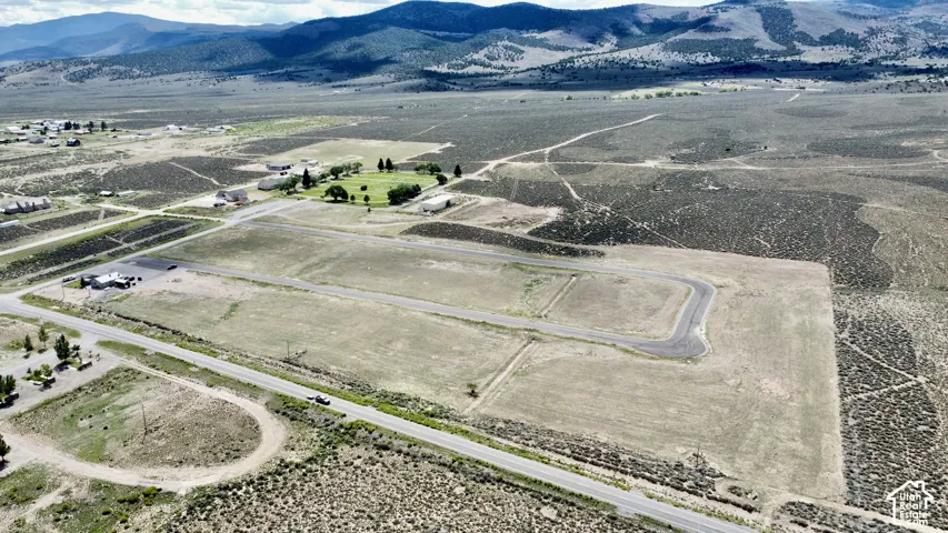 Aerial perspective showcasing expansive land parcels, paved access roads, and distant mountain ranges