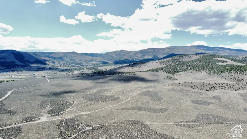 Expansive open land with undulating terrain and distant mountainous backdrop