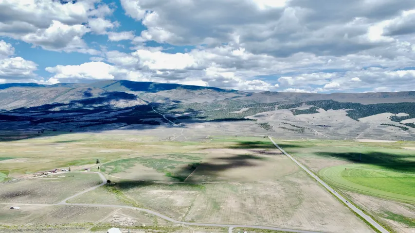 Expansive open terrain with distant mountains, featuring a visible road and cultivated fields