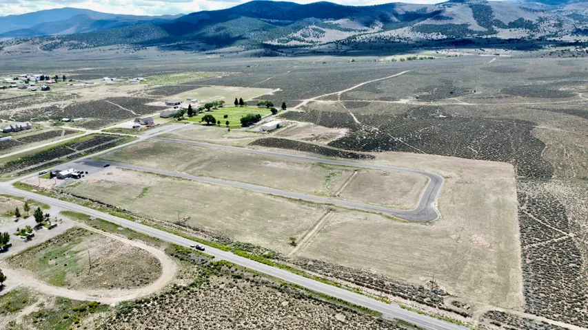 Aerial perspective showcasing expansive land parcels, paved access roads, and distant mountain ranges