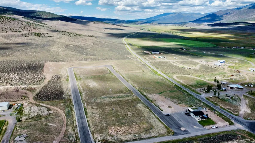 Expansive land featuring paved roadways, surrounding natural terrain, distant mountains, and scattered structures