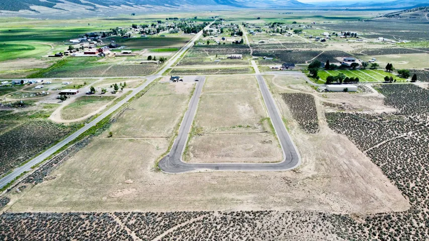 Expansive undeveloped land featuring paved roads and open fields, with distant mountains providing a natural backdrop