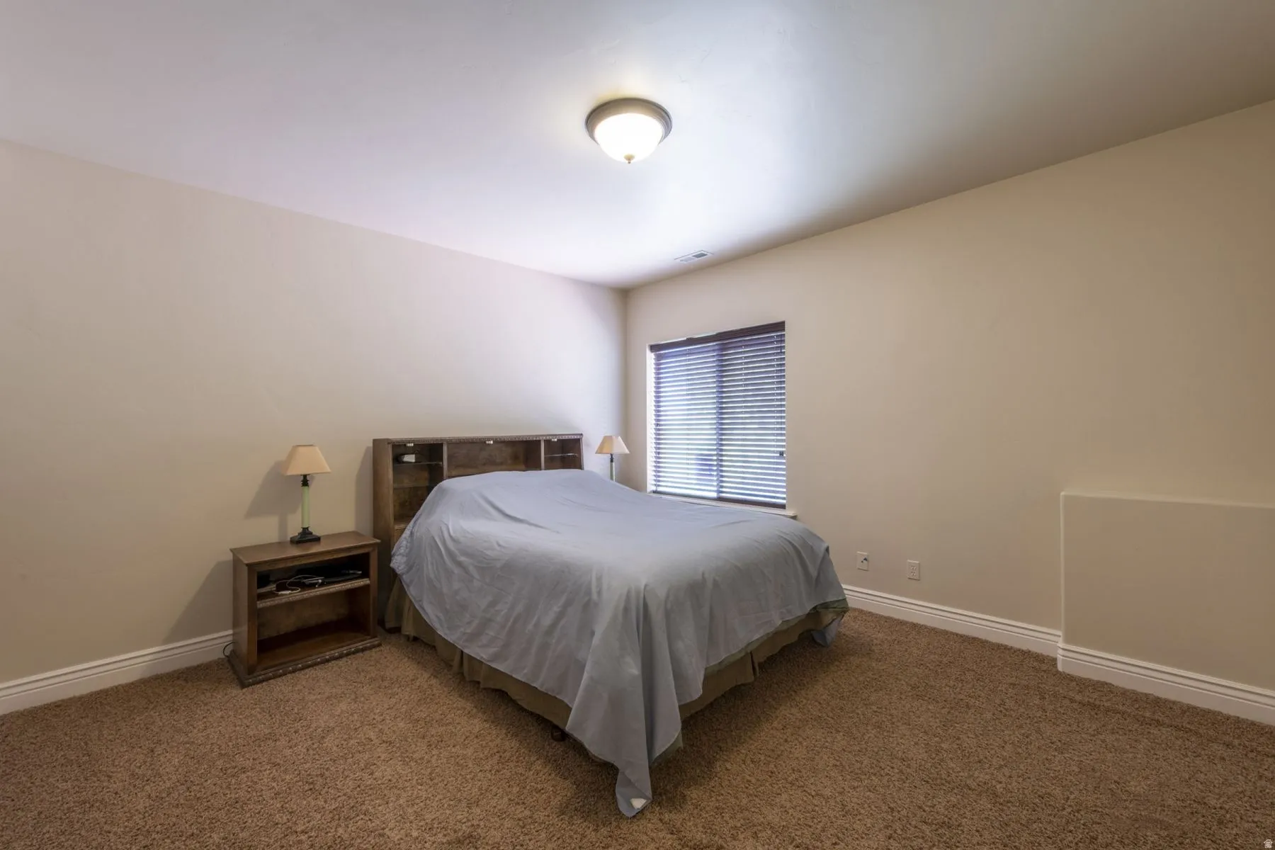 Carpeted bedroom featuring neutral wall tones and a window with blinds